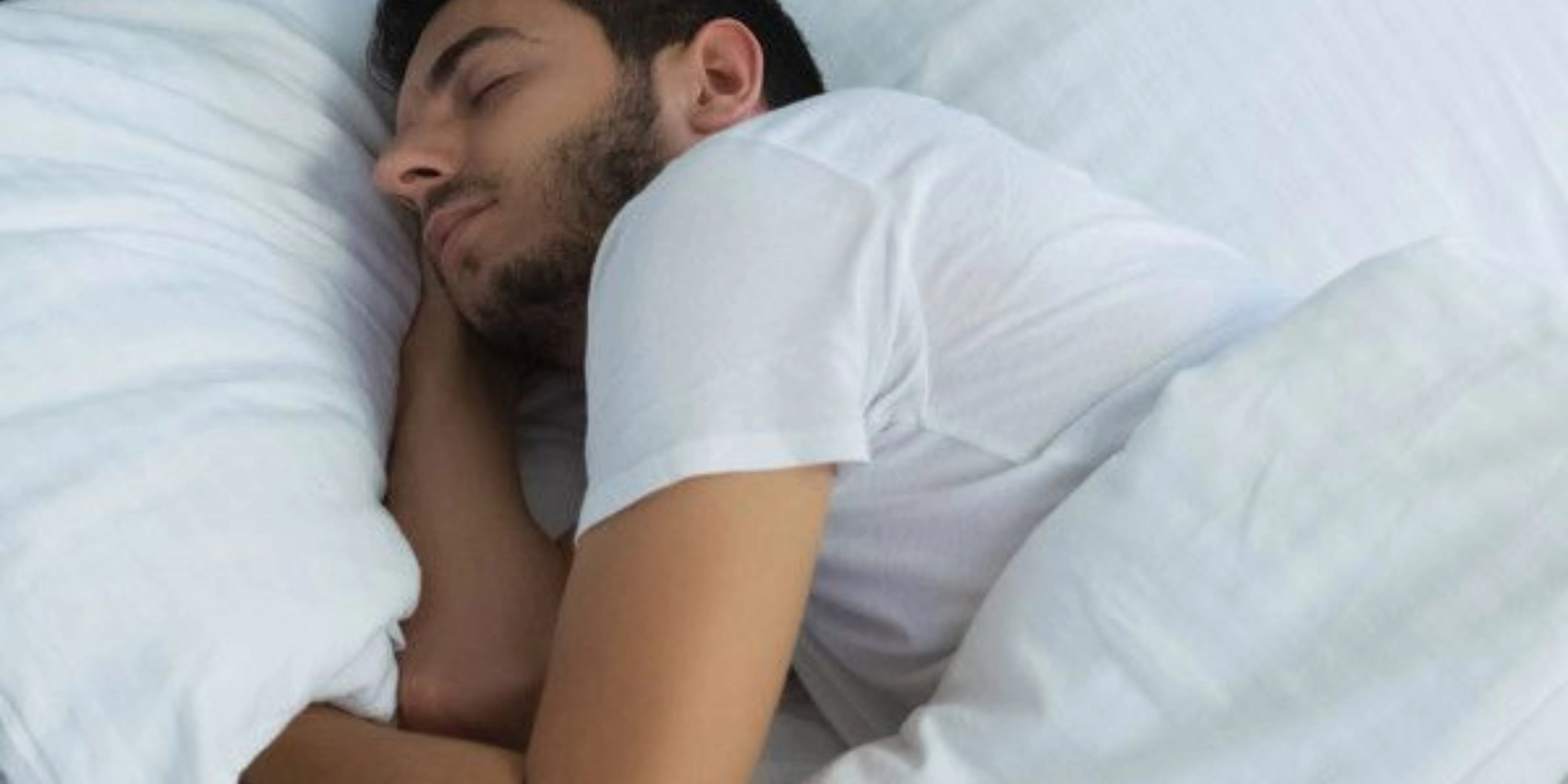 Homme qui dors sur un matelas avec une couverture Image